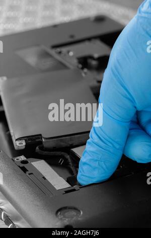 Technician connecting hard drive HDD cable to a laptop computer.  Computer updrade concept Stock Photo