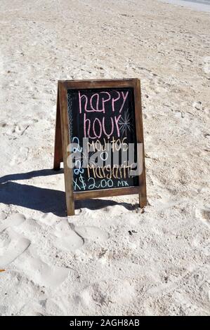 A Happy Hour Sign in the sand on Tulum Beach in Mexico. Stock Photo