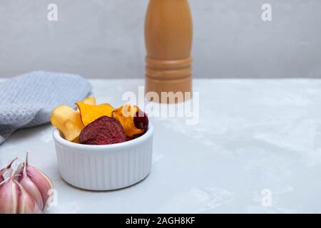 Healthy vegetarian chips made from beetroot, carrots, sweet potatoes, parsnips on neutral concrete table Stock Photo