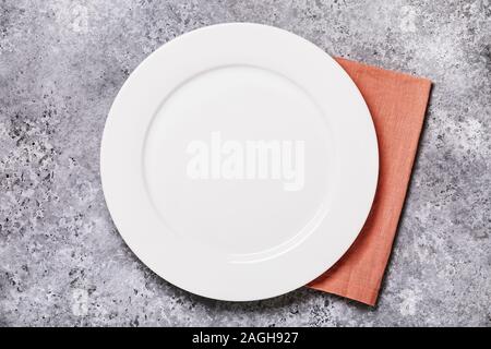 Empty ceramic plate of white color with a napkin on a gray concrete table, top view. Food background Stock Photo