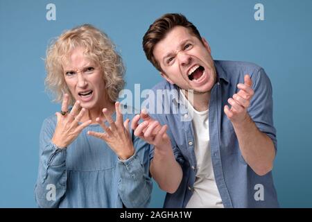 Young man and mature woman with a mad aggressive expression screaming Stock Photo