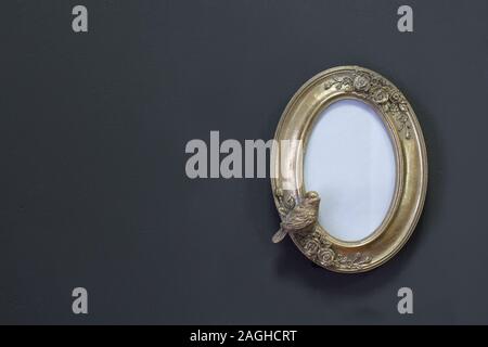 Empty gold vintage oval frame in Victorian style on a gray wall, background or concept Stock Photo
