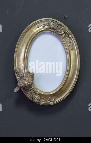 Empty gold vintage oval frame in Victorian style on a gray wall, background or concept Stock Photo