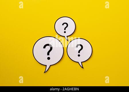 Three speech bubbles with question marks a bright yellow background Stock Photo