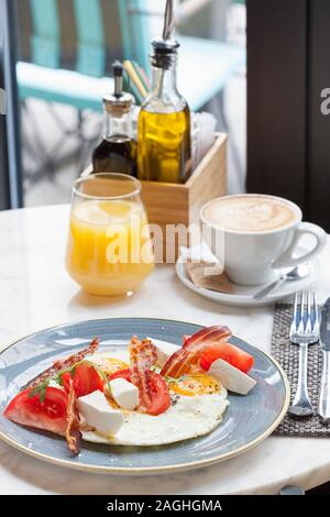 Delicious English breakfast with eggs, bacon and white cheese served in a restaurant with orange juice and cup of coffee Stock Photo