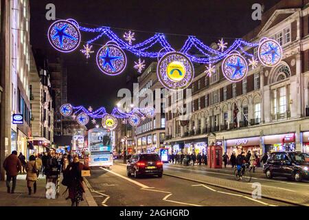 Shoppers and commuters in The Strand, illuminated by decorative Christmas lights, London, UK Stock Photo