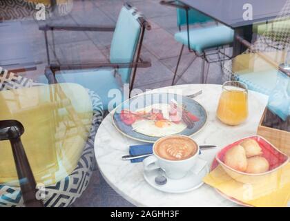 Delicious English breakfast with eggs, bacon and white cheese served in a restaurant with orange juice and cup of coffee Stock Photo