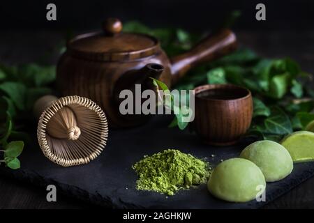 Japanese traditional tea matcha in wooden teapot with bamboo whisk and sweet rice cakes mochi Stock Photo