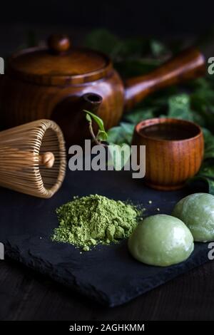 Japanese traditional tea matcha in wooden teapot with bamboo whisk and sweet rice cakes mochi Stock Photo