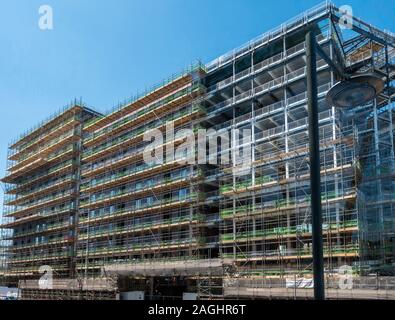 The Wullcomb, a large block of luxury city centre flats under construction with scaffolding and blue sky above, Highcross, Leicester, England, UK Stock Photo