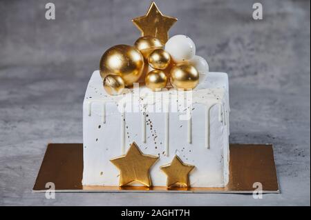 Golden white Christmas cake with chocolates golden and bronze balls. Isolated on grey Stock Photo
