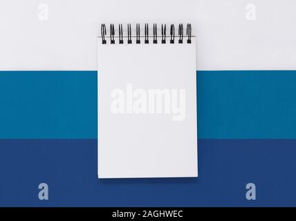 Open notepad on a striped blue and white background, with copy space Stock Photo