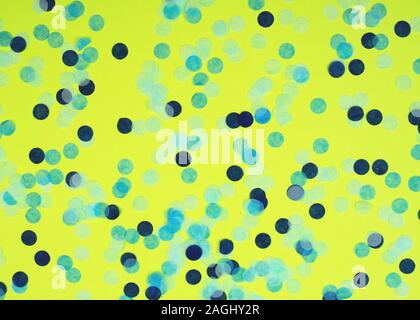 Festive multicolored confetti scattered on yellow background. Holiday concept. Pastel polka dots texture. Stock Photo