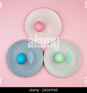 Easter multi-colored eggs and feathers on pink background. Stock Photo