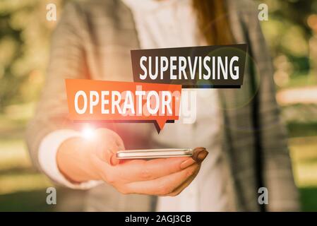 Text sign showing Supervising Operator. Business photo showcasing monitoring and coordinating the plant operations Woman in grey suites holds mobile p Stock Photo