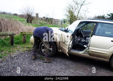March 2019 - Mature man checking the tyres of his car Stock Photo