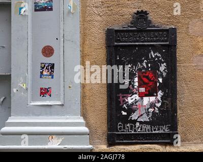 graffiti and stickers on grey painted column and black civic notice board in Old Town of San Sebastian,Northern Spain,Europe Stock Photo