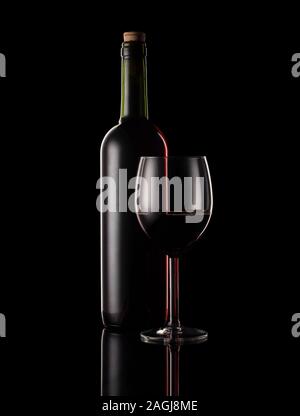 Red wine bottle and glass with black background and rim lighting. Stock Photo