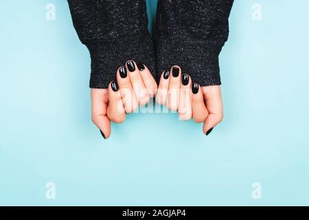 Hands with black manicure in long sleeve. Cozy lifestyle. Flat lay style. Stock Photo