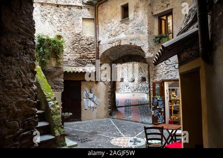 A picturesque courtyard with medieval knight images and gift shop in the ancient center of the medieval hilltop village of Dolceacqua, Italy Stock Photo