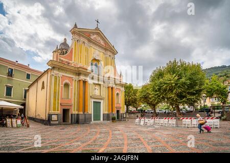 A tourist passes by the Sant Antonio Abate Church in a small piazza on an overcast day in Dolceacqua, Italy Stock Photo