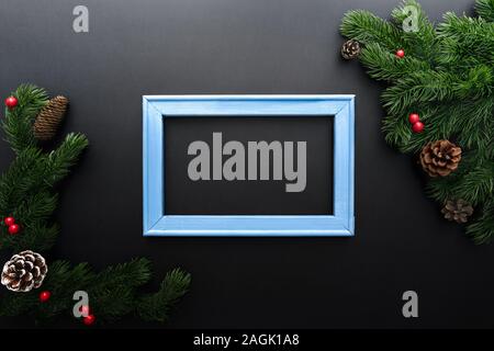 Christmas pine tree and photo frame with xmas decoration on black background Stock Photo
