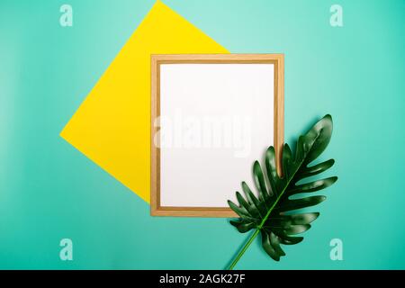 Summer composition. Tropical palm leaves, yellow paper blank, photo frame on pastel green background. Stock Photo