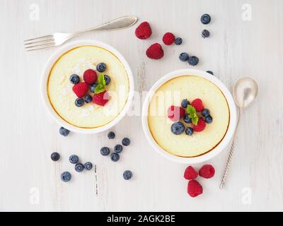 cheesecake decorated with raspberries, blueberries and mint in two ramekin, delicious dessert for a breakfast, top view Stock Photo