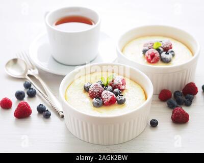 cheesecake decorated with raspberries, blueberries and mint in two ramekin, delicious dessert for a breakfast, side view Stock Photo
