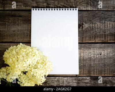 White open empty Notepad and a bouquet of flowers delicate purple hydrangea on a vintage old wooden grey background, mock up. Stock Photo
