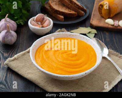 carrot puree, mashed of roasted carrot in white plate on a dark wooden background, side view Stock Photo
