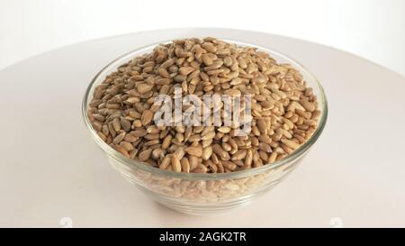 Nuts sunflower rotate are on a table in a plate. Snack in transparent dish on an isolated white background are spinning moving. Stock Photo