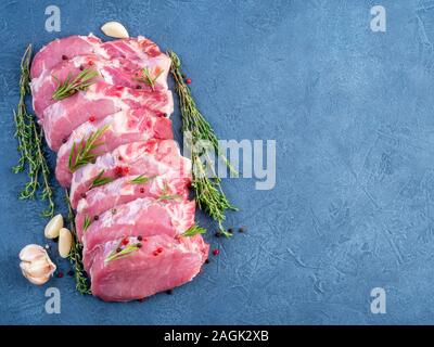Pork steak, raw carbonate fillet on dark background, meat with seasonings, top view, copy space. Stock Photo