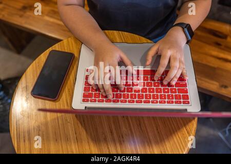 Human hand typing on laptop keyboard next to smartphone Stock Photo