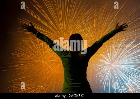 Woman with Arms Outstretched Against Fireworks in Long Exposure in Ticino, Switzerland. Stock Photo
