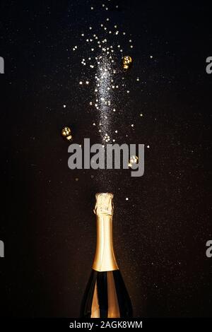 Festive Christmas background. Bottle of champagne with a spray of sparkles and Christmas decorations. Stock Photo