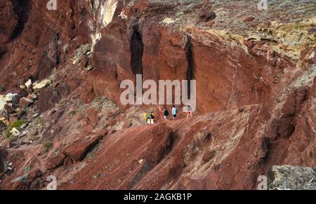 Santorini, Greece - Oct 10, 2018. Trekking on the red volcano mountain near red beach on Santorini Island, Greece. Stock Photo