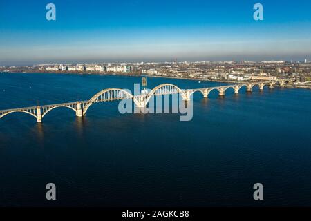 Aerial panoramic view on old arch railway Merefo-Kherson bridge across the Dnieper river in Dnepropetrovsk. View of the left bank of Dnipro city. Stock Photo