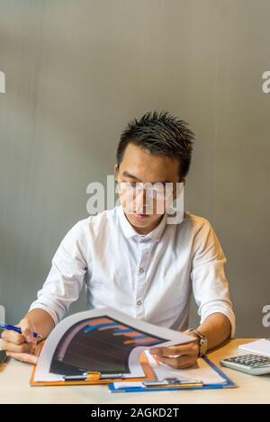 Young businessman wearing glasses focus on analyzing chart documents Stock Photo