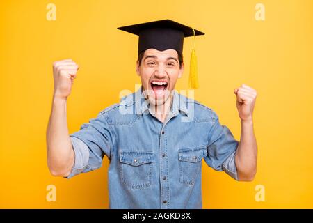 Photo of trendy stylish cheerful man rejoicing in graduating from university screaming making fists shouting isolated vivid color yellow background Stock Photo