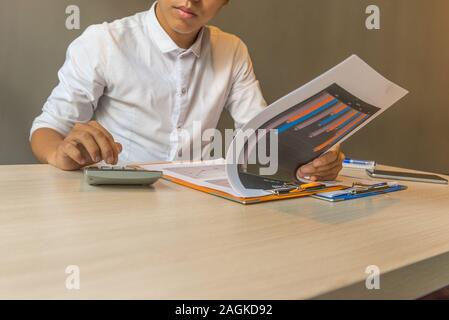 Financial accountant analyzing chart document data on calculator Stock Photo