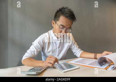 Young businessman checking data on tablet and financial report  Stock Photo