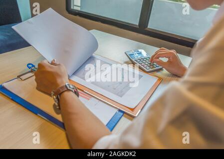 Financial accountant reading sales document and using calculator Stock Photo