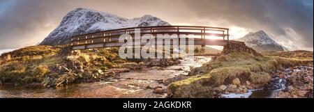 Popular wooden footbridge over the River Coupall in the Glen Coe valley. Amazing scottish landscape at Achnambeithach in Glencoe, Highlands, Scotland Stock Photo