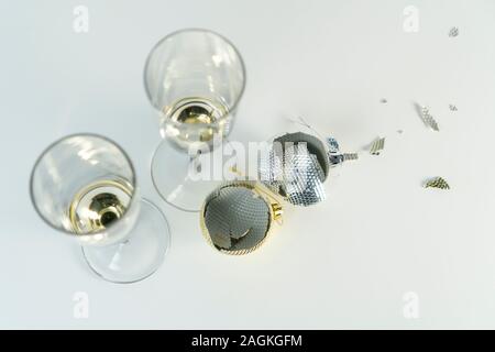 Two broken yellow and gray Christmas balls and a pair of glasses with the remains of champagne on a white table. View from above. The concept of break Stock Photo