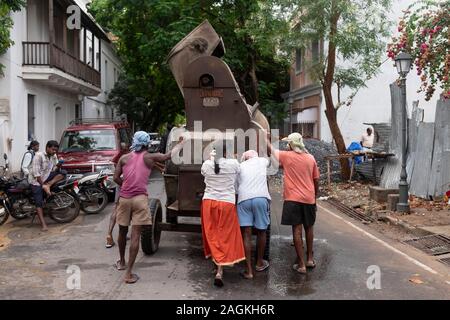 Construction workers pushing a machine in Puducherry, Tamil Nadu, India Stock Photo