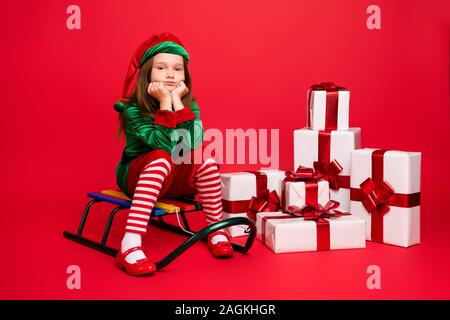 Portrait of her she nice attractive charming tired overwhelmed pre-teen elf Santa Claus apparel look outfit sitting on sled pile stack boxes delivery Stock Photo