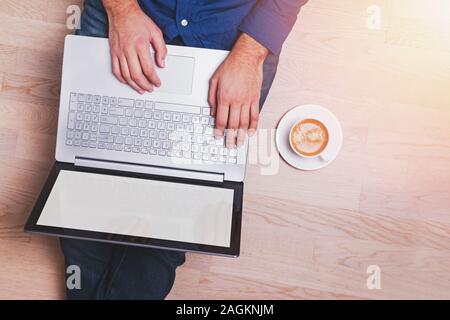 Man sitting on the wooden floor and working on laptop Stock Photo