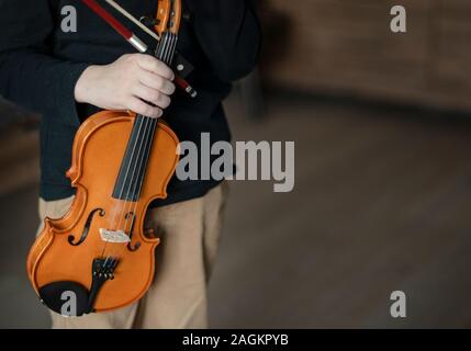 Handle hold violin. Little boy carrying violin. Young boy playing violin, talented violin player. Space for text. Stock Photo