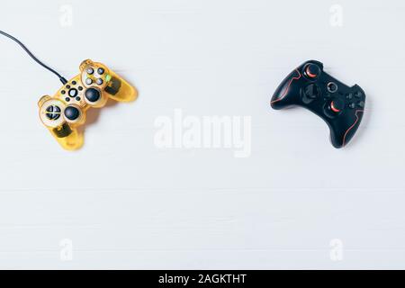 Two gamepads on white wooden background, flat lay composition with copy space. Stock Photo